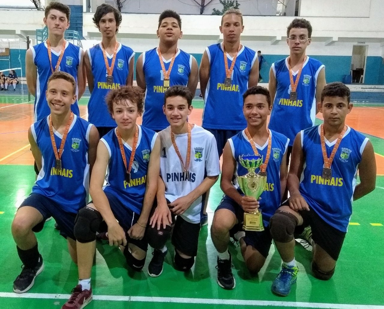 Players lined up for a photo, along with coaches, with the court in the background